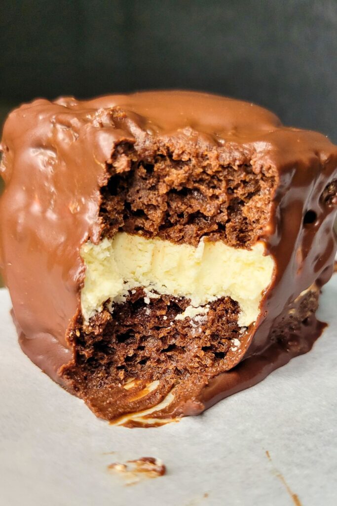 chocolate sourdough snack cake made with fresh milled flour dipped in chocolate ganache with a bite out of the center showing the sourdough filling