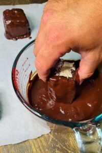 hand dipping the fresh milled flour sourdough snack cakes into the homemade chocolate ganache