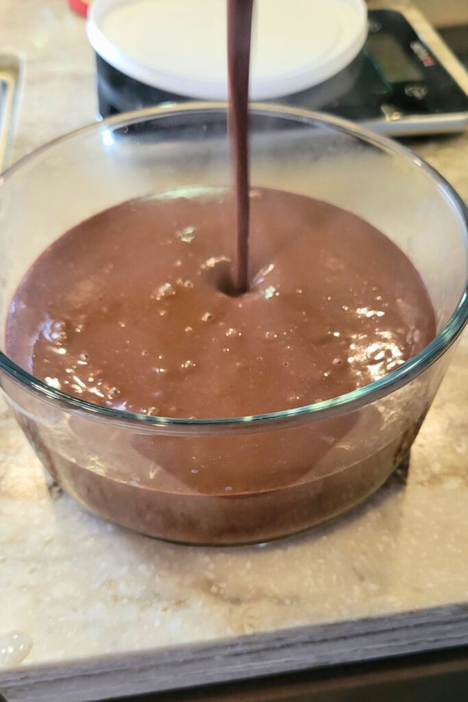 pouring the hot fresh milled flour chocolate pudding into a heat safe bowl