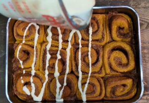 drizzling the icing on the fresh milled flour pumpkin cinnamon rolls