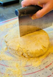 hand dividing the dough with a dough scraper