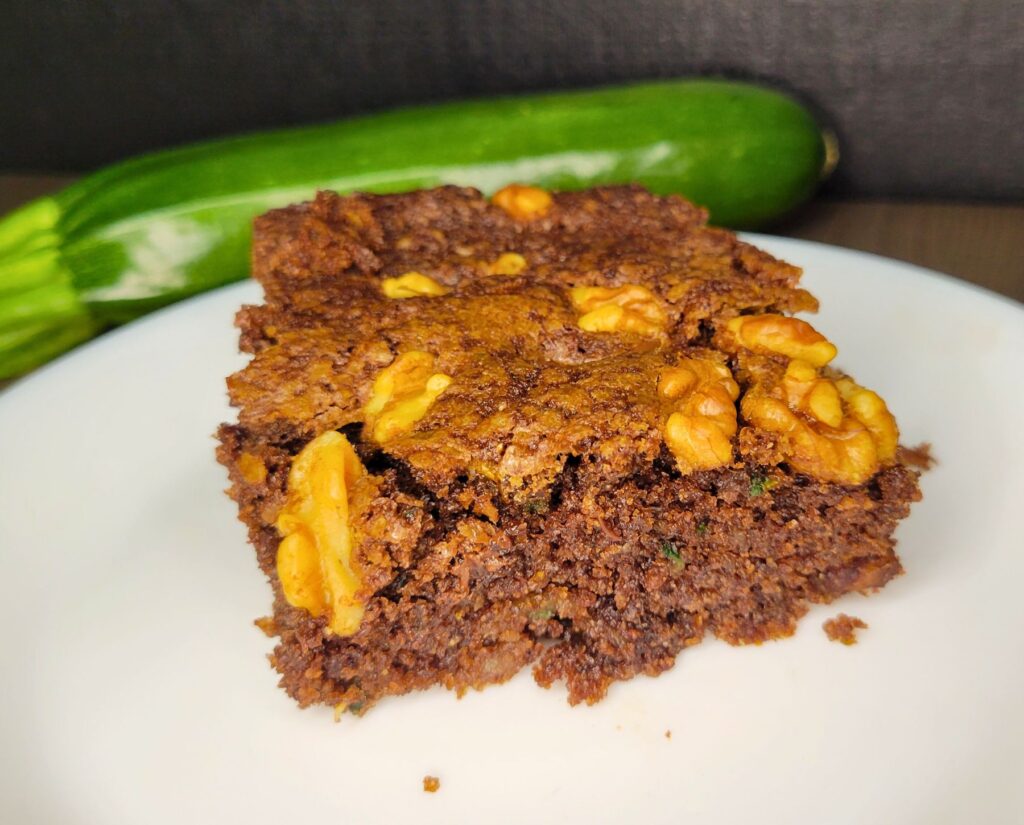chocolate zucchini cake slice made with fresh milled flour and topped with chopped walnuts