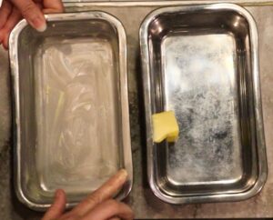 hands buttering stainless steel loaf pans