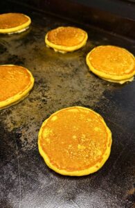 fresh milled flour pumpkin pancakes being cooked on a flat griddle