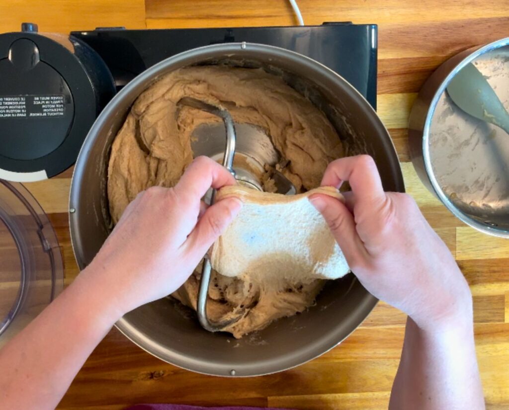 hands showing stretchy dough in a kitchen mixer